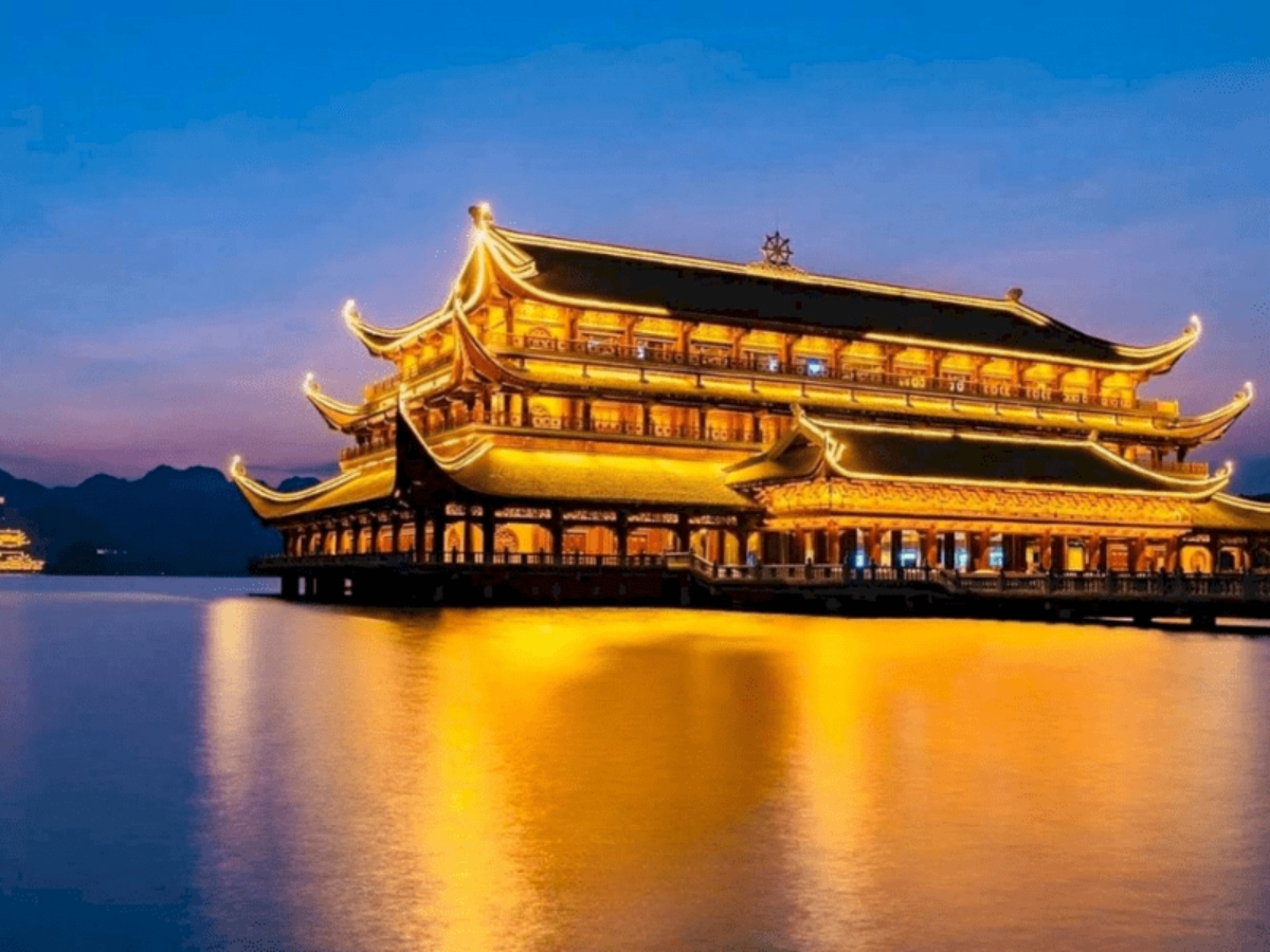Chùa Bái Đính nổi bật giữa mặt hồ dưới ánh đèn vàng rực rỡ khi màn đêm buông xuống.