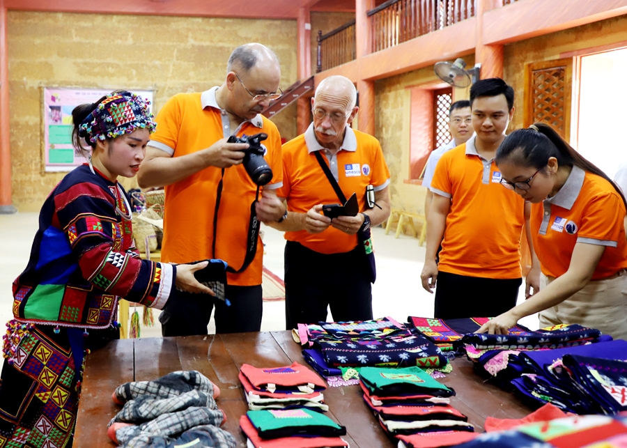 Hướng dẫn viên du lịch giới thiệu vải thổ cẩm cho du khách.