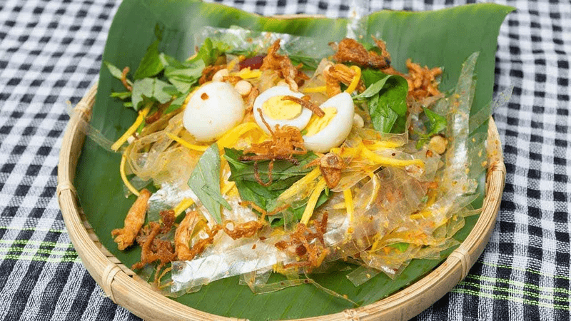Cận cảnh một phần bánh tráng trộn gồm bánh tráng, xoài xanh, trứng cút, bò khô, hành phi và trộn nước cốt tắc