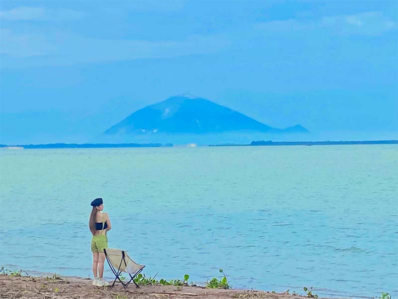 Du khách đi dạo và ngắm cảnh ven hồ Dầu Tiếng và núi Bà Đen phía xa 