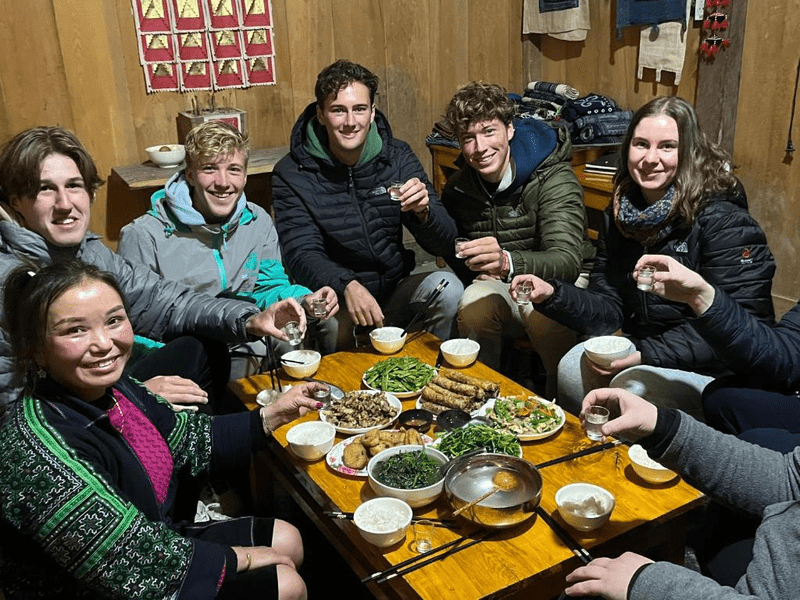 Du khách và chủ nhà cùng nhau dùng bữa tối và thưởng thức rượu ngô (Nguồn: Big Tree Hmong Homestay)