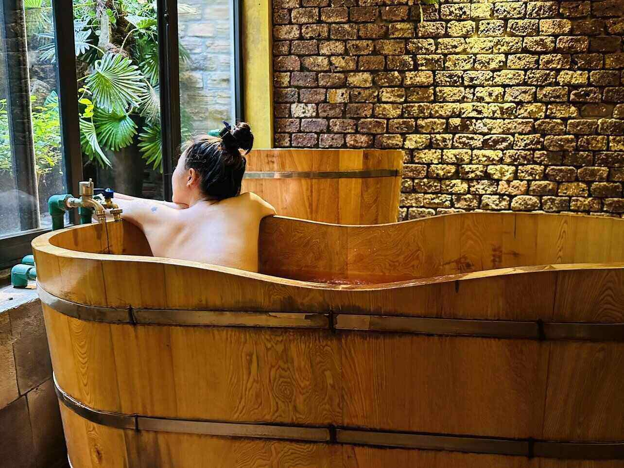 Du khách trải nghiệm ngâm mình thư giãn trong bồn tắm nước lá Dao Đỏ. (Nguồn: Sưu tầm)