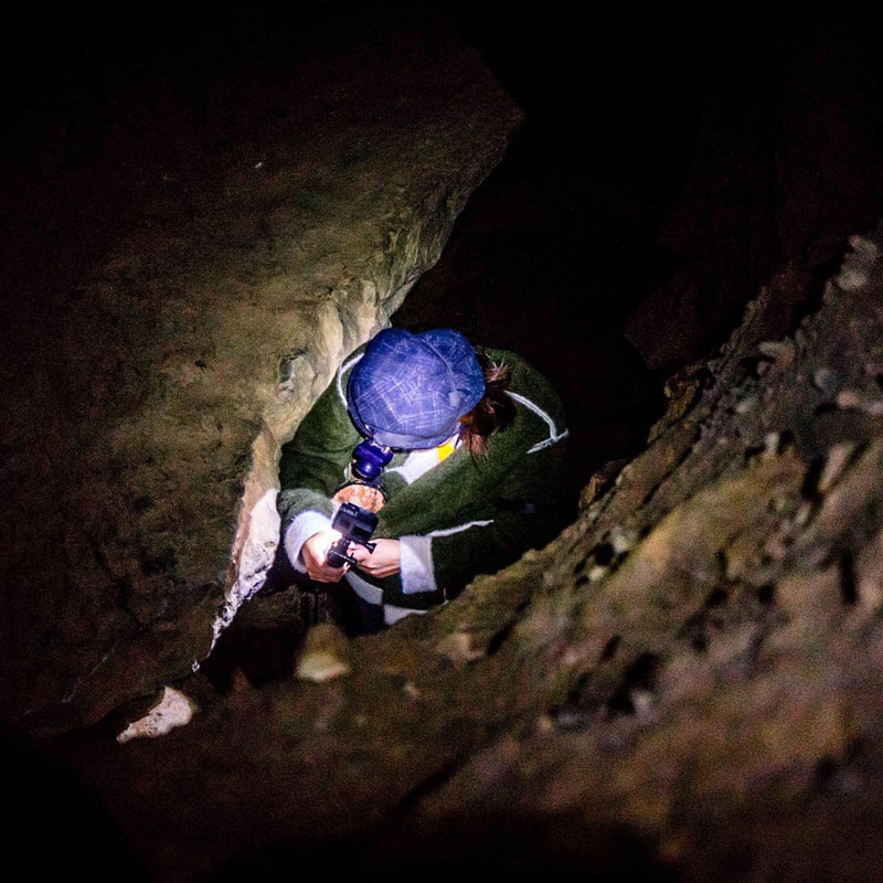 Du khách cẩn thận luồn lách bên trong hang động nhỏ hẹp