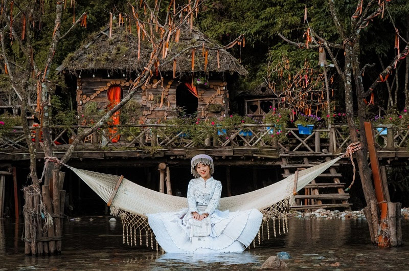 Du khách tạo dáng chụp ảnh bản Cát Cát với chiếc võng đan thủ công