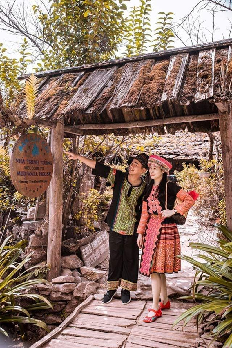 Du khách lưu lại khoảnh khắc tại cổng vào nhà trình tường của người H’Mông với trang phục bản Cát Cát
