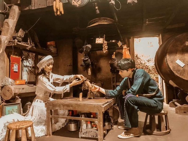 Đôi bạn trẻ cùng nhau thưởng rượu bên trong không gian sinh hoạt của người đồng bào