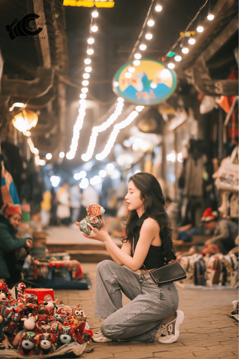 Nữ du khách chăm chú lựa chọn búp bê thổ cẩm để mang về làm quà 