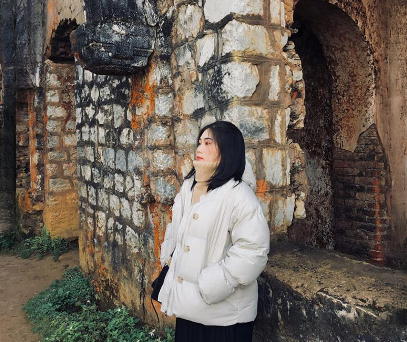 Du khách chụp ảnh tại bức tường cũ màu rêu cam độc đáo