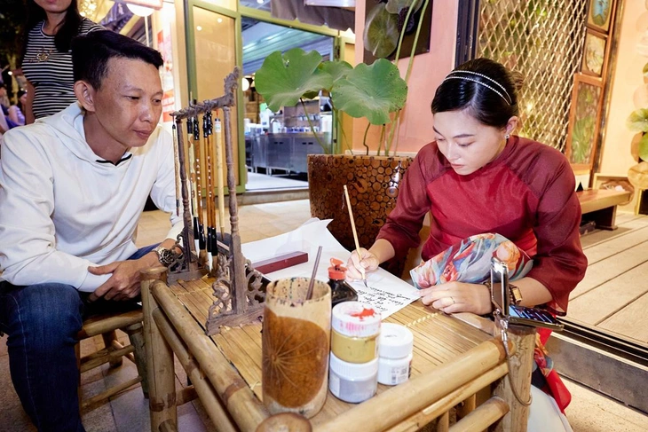 Du khách trải nghiệm viết thư pháp tại chợ đêm Vui Fest 