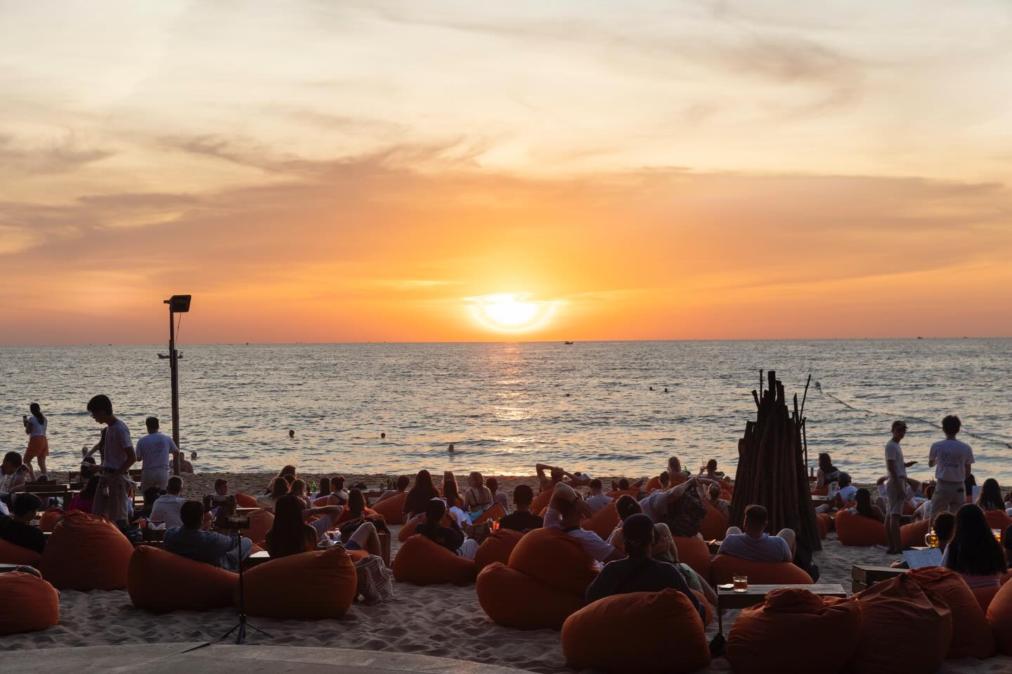 Du khách thư giãn trên ghế lười và ngắm hoàng hôn buông trên biển