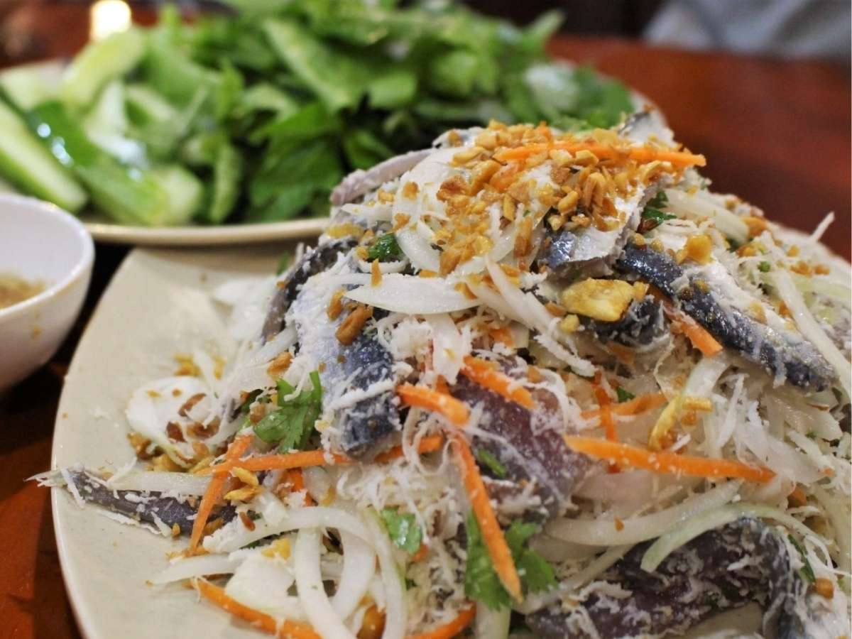 Món gỏi cá trích đặc sản ăn kèm rau sống và bánh tráng.