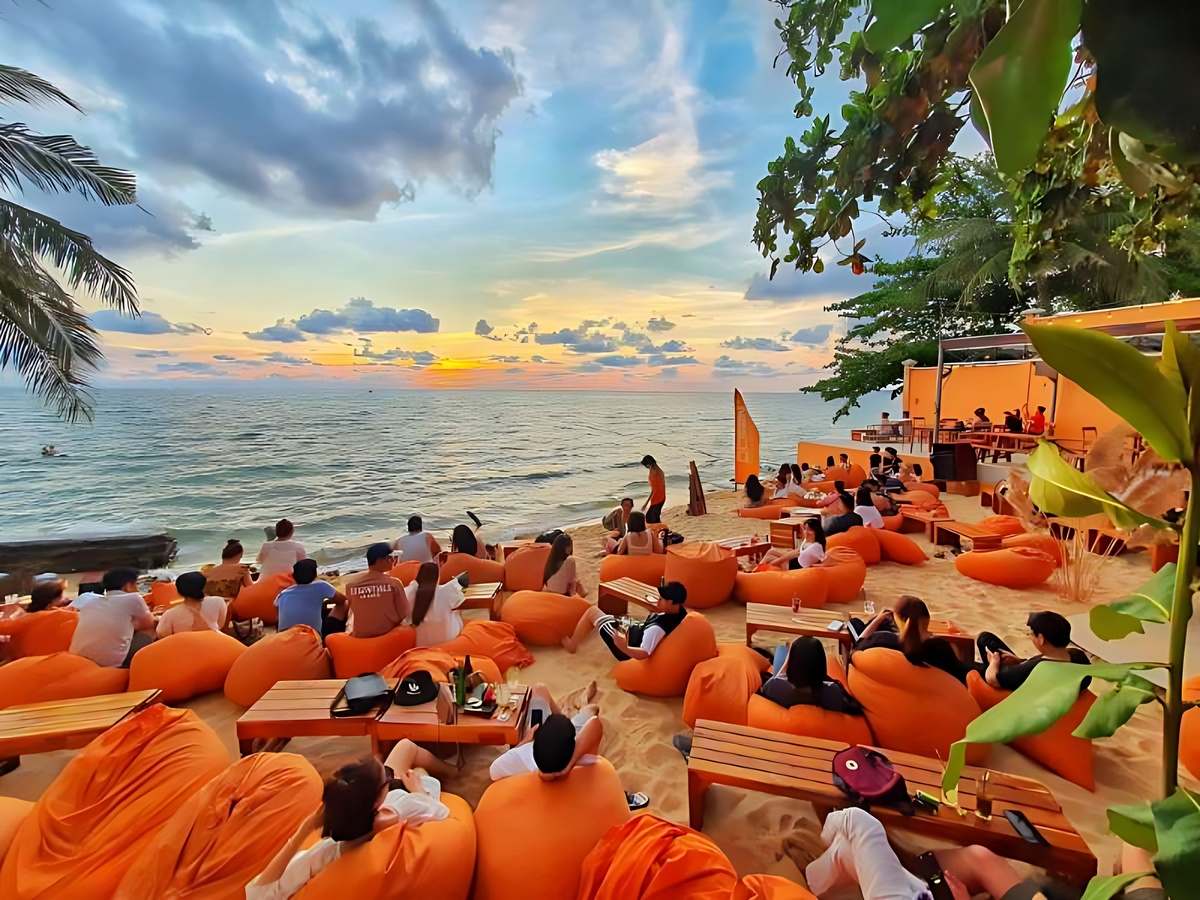 Du khách ngồi trên ghế lười tông cam ngắm cảnh biển tại OCSEN Beach Bar & Club
