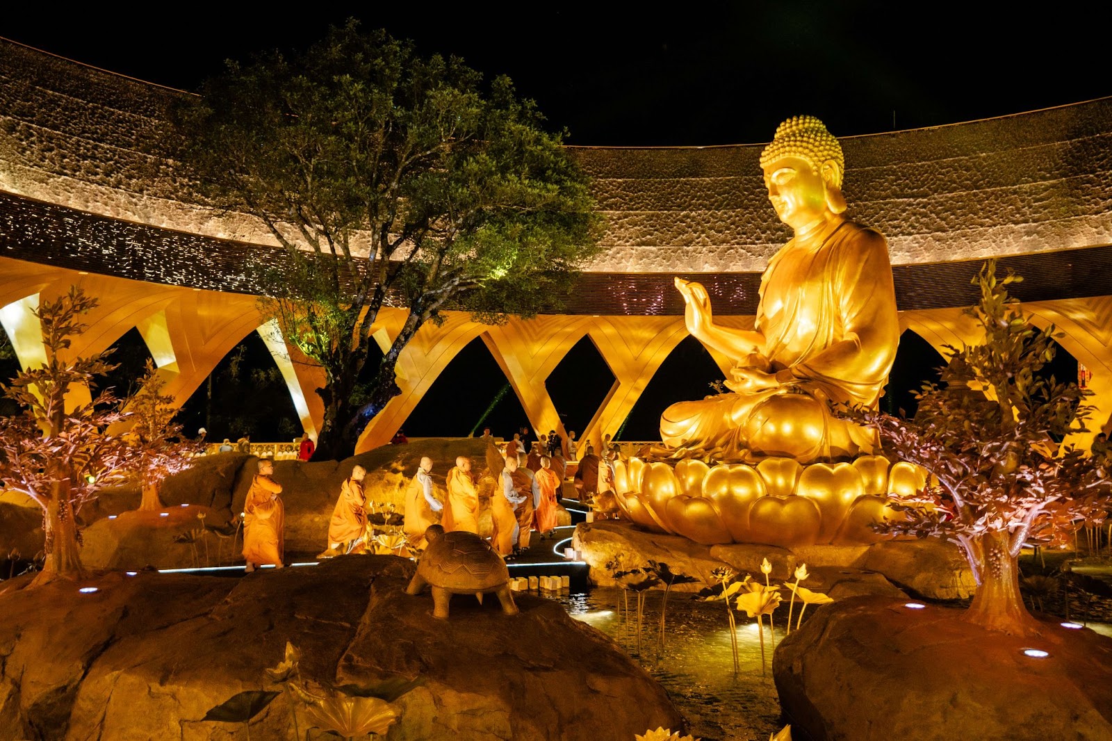 Tôn tượng Đức Phật Câu Na Hàm Mâu Ni được tạo tác bên gốc sung cổ có tuổi đời nhiều thập kỷ, soi bóng xuống hồ Ưu đàm