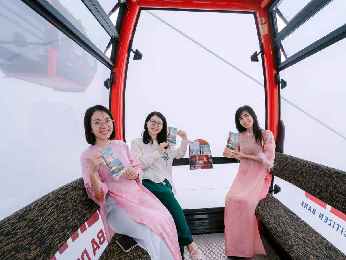 Du khách chụp ảnh trong cabin cáp treo giữa khung cảnh mây trắng.
