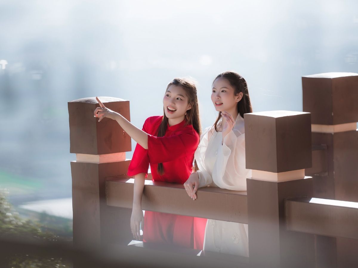 Du khách tạo dáng bên lan can trong ánh sáng sớm trên đỉnh núi.