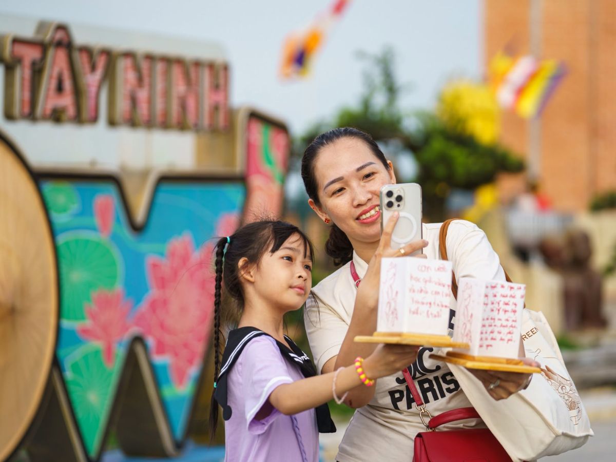 Hai mẹ con vui vẻ chụp ảnh kỷ niệm cùng đèn hoa đăng trước biểu tượng Tây Ninh.