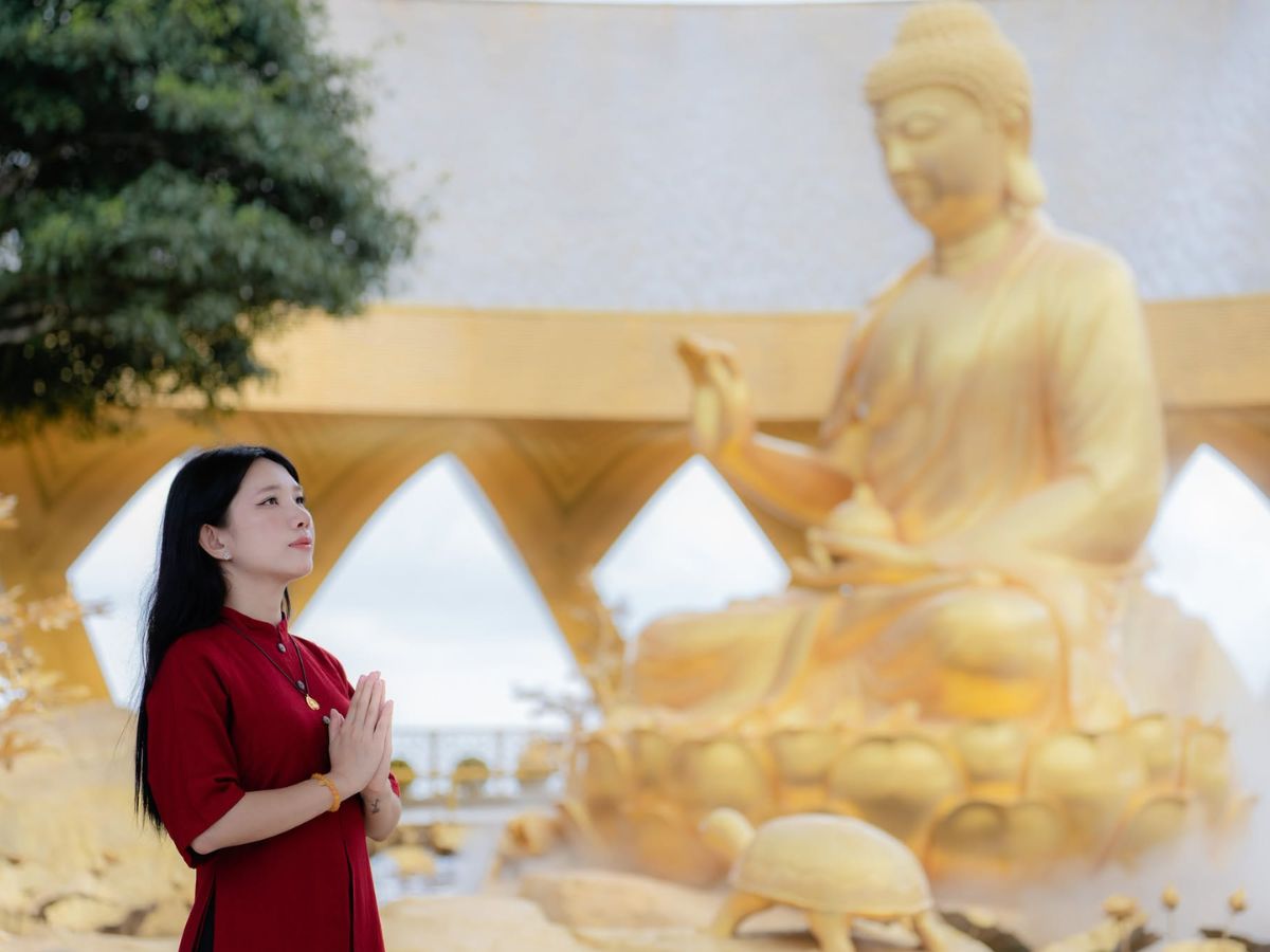 Du khách chiêm bái bên tôn tượng Đức Phật Câu Na Hàm Mâu Ni tại Vườn Ưu Đàm.