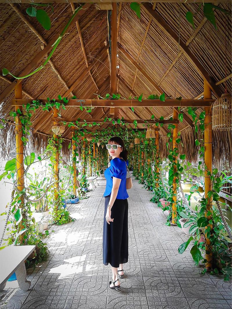 Du khách check-in tại lối đi lợp mái lá trong khu du lịch (Nguồn: Vui chơi giải trí sinh thái & Ẩm thực Long Trung)