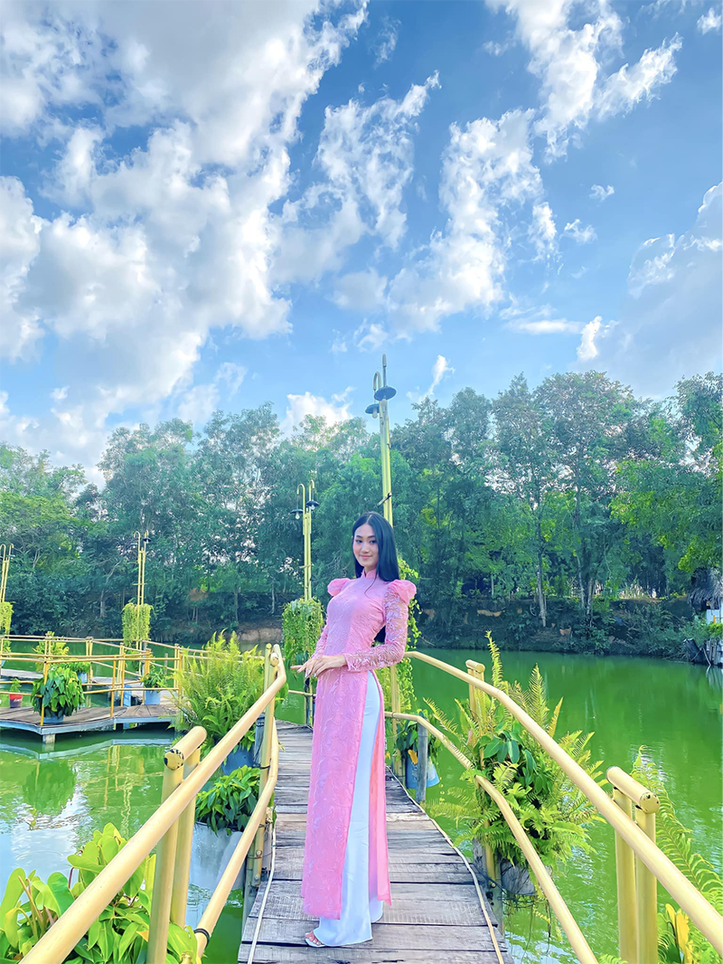 Du khách vui vẻ tạo dáng trên cầu tre bắc qua hồ nước trong tà áo dài thướt tha (Nguồn: Vui chơi giải trí sinh thái & Ẩm thực Long Trung)